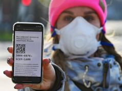 Девушка в медицинской маске демонстрирует на экране мобильного телефона своей цифровой пропуск с QR-кодом на передвижение по территории Москвы. Фото: Игорь Иванко / Коммерсант